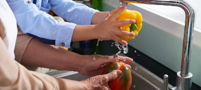Hands washing a yellow Bell Pepper.