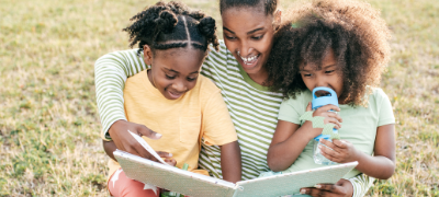African American woman reading with two daughters.