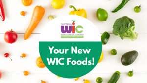 A professional announcement graphic with a vibrant background of assorted fresh vegetables including leafy greens, bell peppers, and root vegetables. In the center of the image, a large white circle contains bold text that reads: 'New WIC Food Guide.